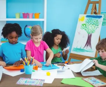 Children cutting paper and drawing at an art table