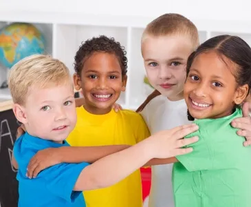 Four smiling children with their arms around each other