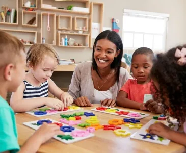 A teacher and children working on shape puzzles together