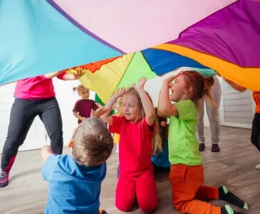 Children playing under a colorful parachute
