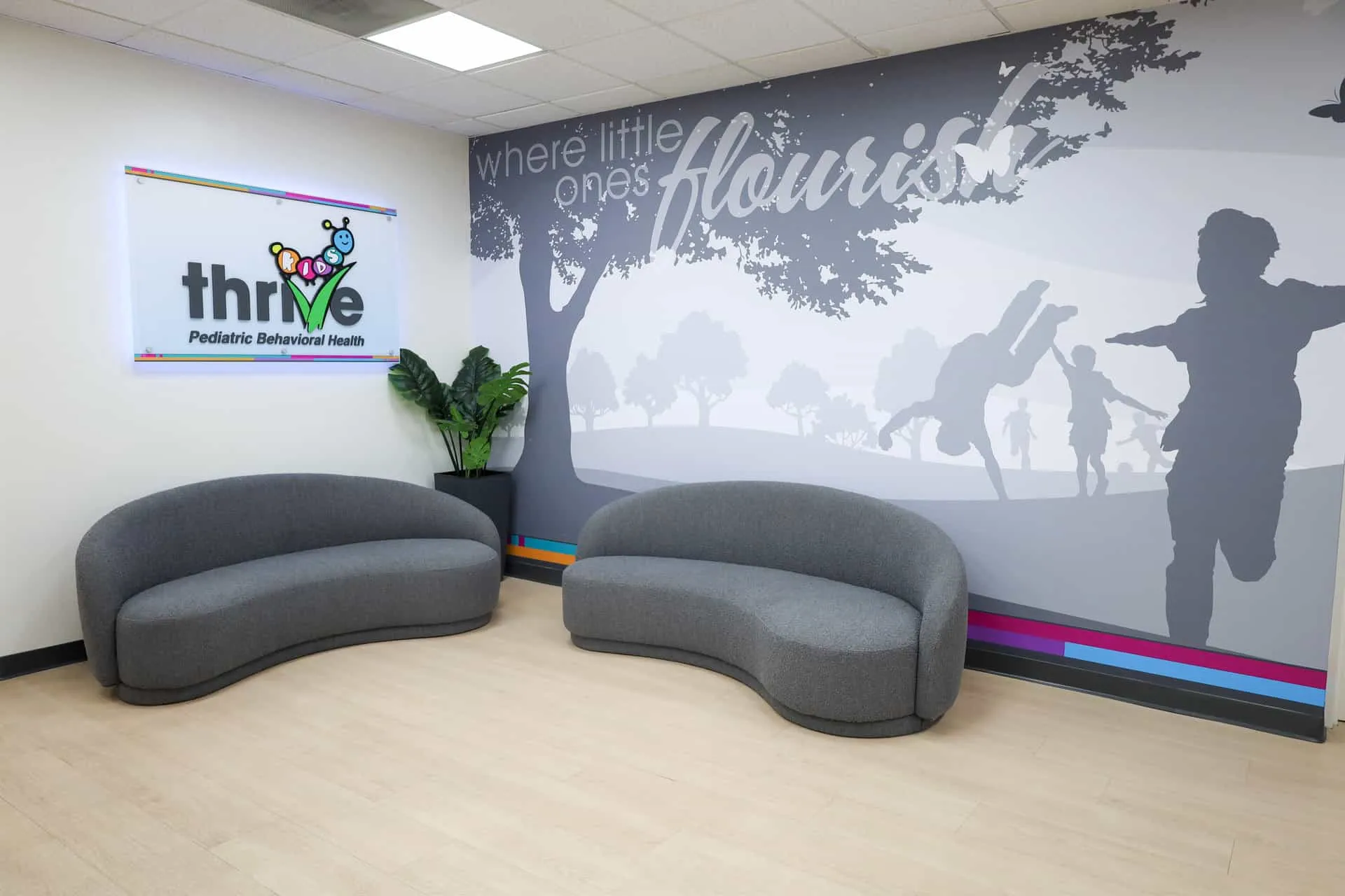 The Kids Thrive lobby, with the Kids Thrive Pediatric Behavioral Health sign and a mural that reads where little ones flourish